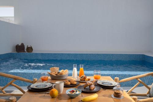 a table with food and drinks in front of a swimming pool at Aegean Melody Suites & Villas in Vlychada