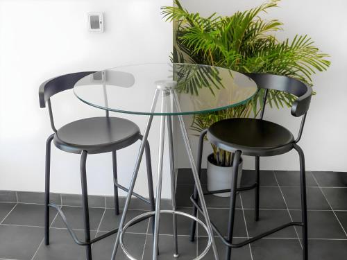 a glass table and two stools next to a plant at Emirates Sports Hotel, Dubai Sports City in Dubai