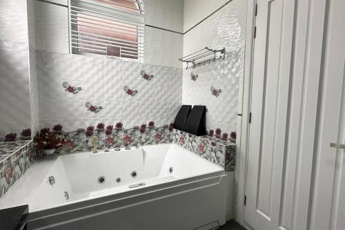 a white tub in a bathroom with flowers on the wall at 21pax KL Event Bungalow in Ampang