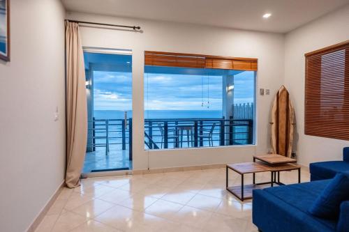 Una sala de estar con un sofá azul y una ventana grande. en Uluwatu Cliff Apartment - 1 BR, en Uluwatu