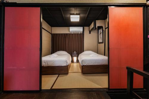 a room with two beds and a sliding glass door at Shiki Homes NATSU in Kyoto