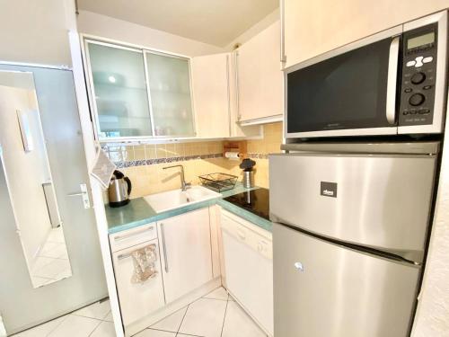 une cuisine avec un réfrigérateur en acier inoxydable et un micro-ondes dans l'établissement APPARTEMENT 1 CHAMBRE 4 PERSONNES EN REZ DE CHAUSSEE DANS RESIDENCE AVEC PISCINE, au Grau-du-Roi