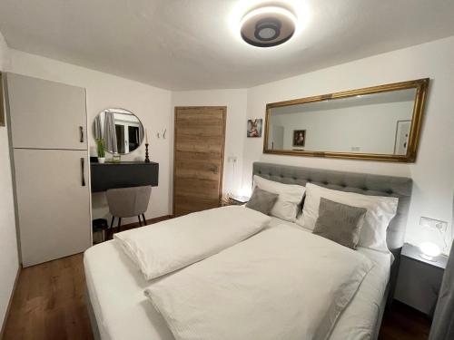 a bedroom with a large white bed and a mirror at Komfort-Apartments Waidring in Waidring