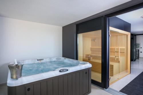a hot tub in a room with a glass door at Deluxe villa with heated pool, whirpool, sea view, beautiful beach IV - by Traveler tourist agency Krk ID 2403 in Krk