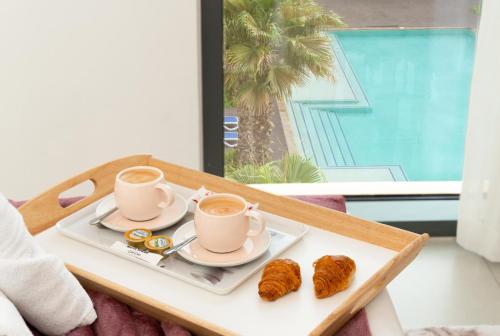 a tray with two cups of coffee and pastries on a table at Modern 1-bedroom apartment in family-friendly residence with Swimming Pool, Gym & Free Parking. in Dubai