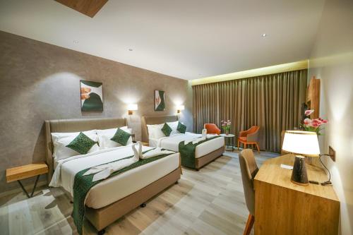 Habitación de hotel con 2 camas y escritorio en Hotel Park Inn, en Nellore