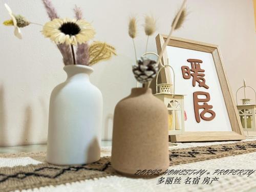 two white vases sitting on a table with flowers at 2 Storey House Bayu Mutiara @ Bukit Mertajam in Bukit Mertajam