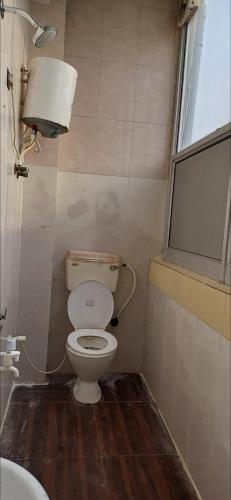 a small bathroom with a toilet and a window at Hotel green in Faridabad