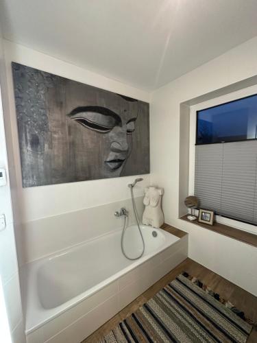沃爾夫根的住宿－Modernes Ferienhaus，浴室配有浴缸,墙上挂有绘画作品