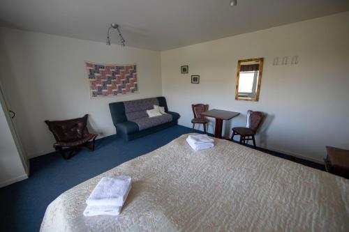 een slaapkamer met een bed, een bank en een tafel bij Hotel Breidavik in Breiðavík