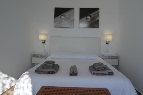 ein Schlafzimmer mit einem weißen Bett und Handtüchern darauf in der Unterkunft EL ENCANTO II PISCINA PRIVADA WIFI BARBACOA PARKING AIRE Ac in Chiclana de la Frontera