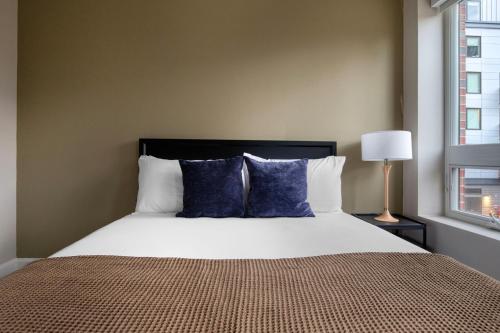 a bedroom with a large bed with blue pillows at Kendall Square studio w gym wd rooftop BOS-918 in Boston