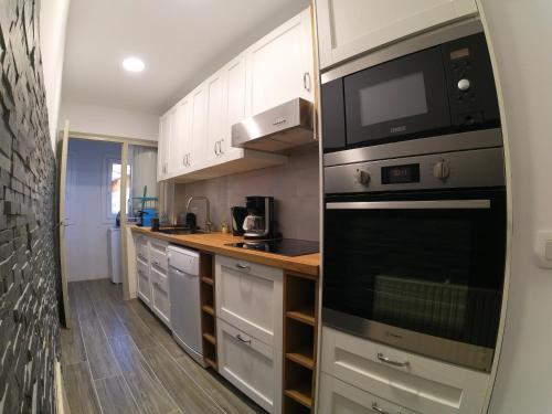 a kitchen with white cabinets and a stove top oven at Soldeu Paradis Soldeu in Soldeu