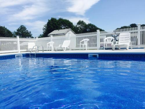 a swimming pool with chairs and a white fence at Ocean Acres Ogunquit in Ogunquit