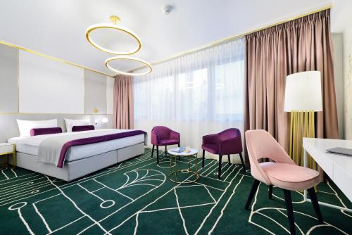 a hotel room with a bed and purple chairs at Hotel Ferreus Modern Art Deco in Kraków