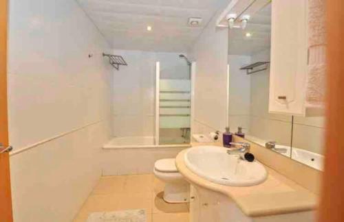 a white bathroom with a toilet and a sink at Wonderful townhouse on Sa Boadella beach in Lloret de Mar