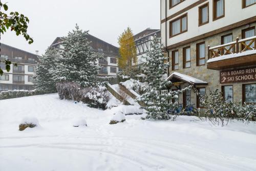 a snow covered yard in front of a building at Green Life Bansko in Bansko