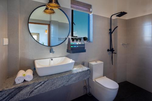 a bathroom with a sink and a mirror and a toilet at Hotel Bay Watch Unawatuna in Unawatuna