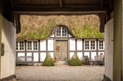 an old building with a grass roof with a door at Solbjerggaard Studio Apartments in Fåborg