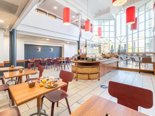 Un comedor con mesas y sillas y una cafetería. en B&B HOTEL Lyon Eurexpo Bron, en Bron