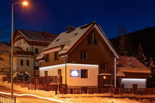 une maison dans la neige la nuit dans l'établissement Woody - Smart Luxury Home, à Karpacz