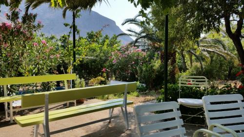 a green bench and chairs in a garden with flowers at Oasis in Kamarai