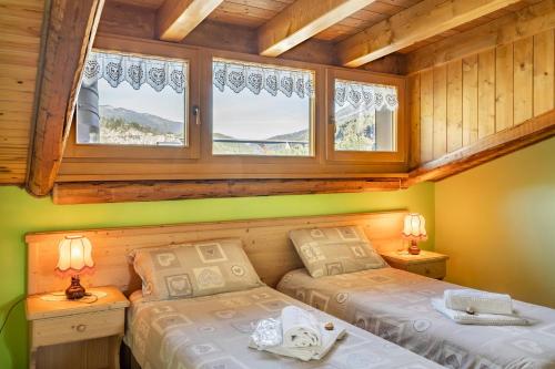 two beds in a room with two windows at B&B La Genzianella in Perarolo di Cadore