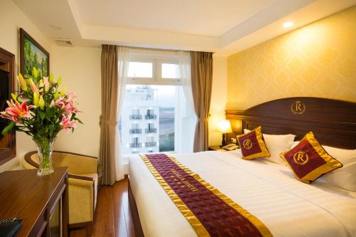ein Hotelzimmer mit einem Bett und einer Vase aus Blumen in der Unterkunft Regalia Nha Trang in Nha Trang