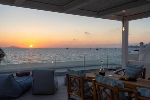 a patio with a view of the ocean at sunset at Aegean Melody Suites & Villas in Vlychada