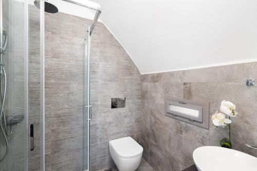 a bathroom with a toilet and a glass shower at Aegean Melody Suites & Villas in Vlychada