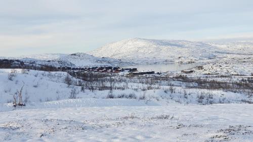 a snow covered mountain with a town and a lake at Katterjåkk Apartments in Riksgränsen
