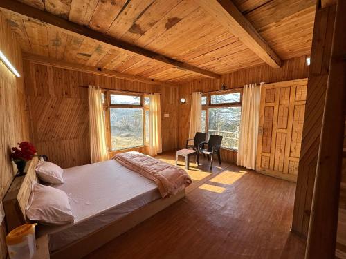 ein Schlafzimmer mit einem Bett in einem Holzzimmer in der Unterkunft Himalayan Mountain View Cottage Deohari in Sainj