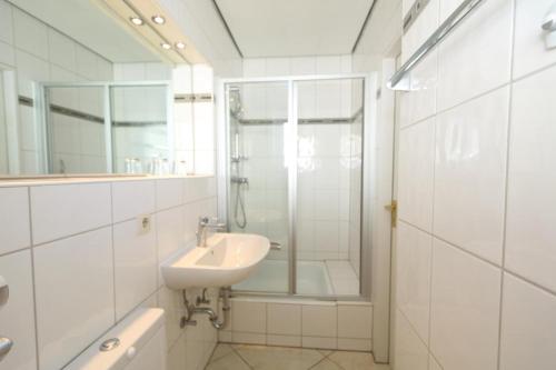 ein weißes Bad mit einem Waschbecken und einer Dusche in der Unterkunft Schwalbe - Tripp in Westerland