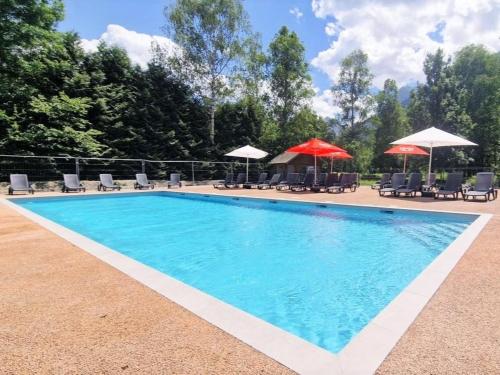 una piscina con sillas y sombrillas en Camping Le Colporteur, en Le Bourg-dʼOisans