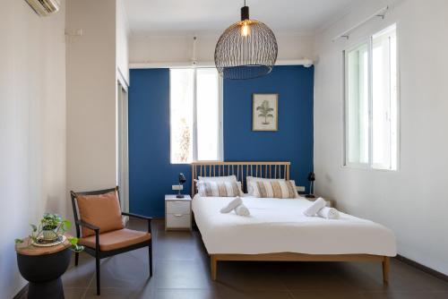 a bedroom with blue walls and a bed and a chair at The Printhouse - Downtown Boutique Apartments by Sea N' Rent in Haifa