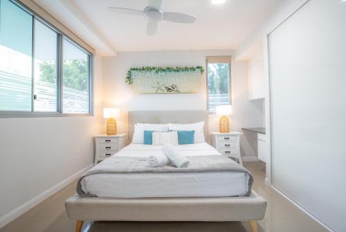 a white bedroom with a bed and two windows at Nova Apartments 104 Mooloolaba Beach in Mooloolaba