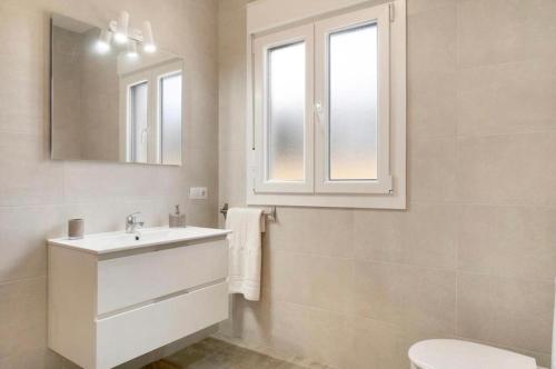 ein weißes Badezimmer mit einem Waschbecken und einem Spiegel in der Unterkunft Villa Montenmedio Paula in El Soto
