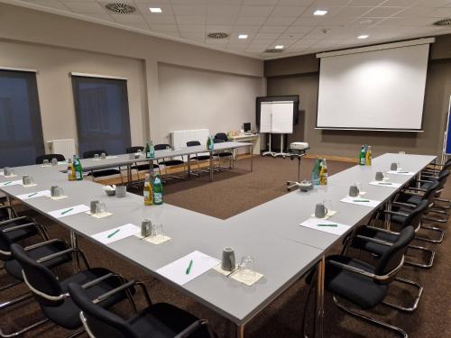 a conference room with a large table and chairs at Kedi Hotel Papenburg in Papenburg