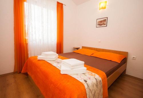 1 Schlafzimmer mit 2 Betten mit orangefarbener Bettwäsche und Handtüchern in der Unterkunft Galerie-Apartment 400 Meter zum Strand in Baška