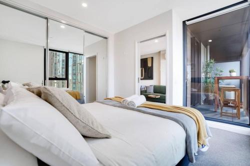 een witte slaapkamer met een groot wit bed en grote ramen bij "Hidden Gem" Cosy 2B apt in central Melbourne#UT2602 in Melbourne