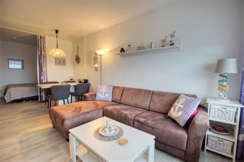 sala de estar con sofá marrón y mesa en Ferienpark - Haus F, App 0F0508, en Heiligenhafen