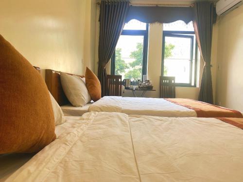 two beds in a hotel room with a window at Sun Hà Giang Hotel-tours-motorbike rental in Ha Giang