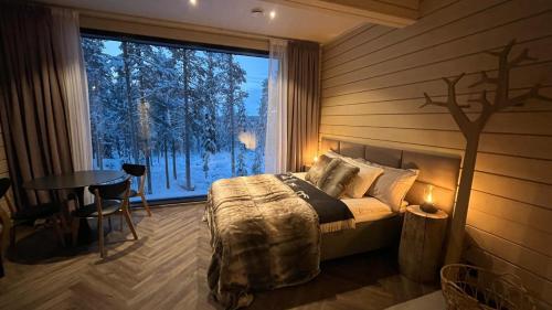 een slaapkamer met een bed, een tafel en een raam bij Invisible Forest Lodge in Rovaniemi