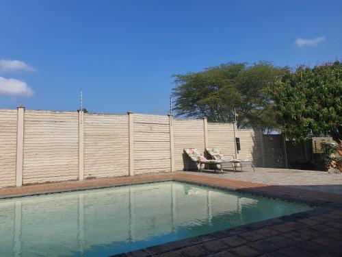 - une piscine avec 2 chaises et une table à côté d'une clôture dans l'établissement Ntoliwa Bed and Breakfast, à Suits Me