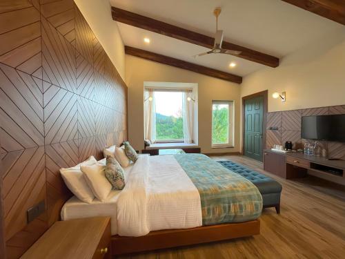 a bedroom with a large bed and a television at The Corbett Greens in Rāmnagar