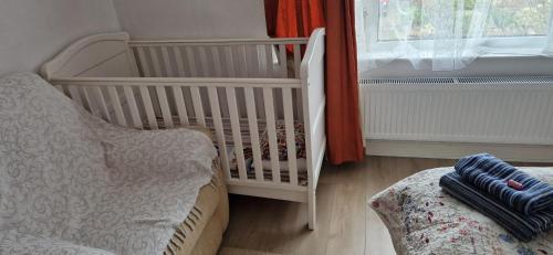 a white crib in a room with a window at Bob's House quiet retreat with large shared garden in Loughborough