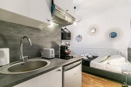 uma cozinha com um lavatório e uma cama num quarto em MBA Splendide Appart - Mowat - Proche Château de Vincennes em Vincennes