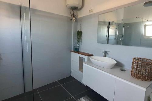 een witte badkamer met een wastafel en een spiegel bij La belle rencontre in Mamoudzou