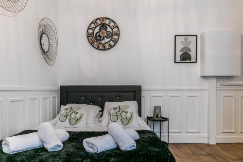 um quarto com uma cama com almofadas brancas e um relógio em MBA Splendide Appart - Mowat - Proche Château de Vincennes em Vincennes