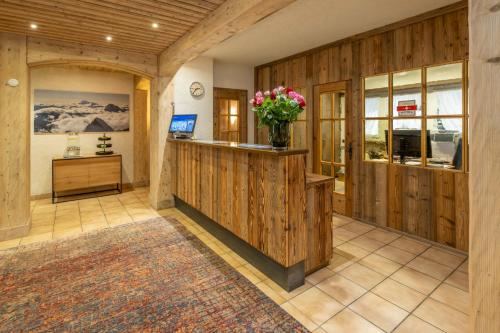 a lobby with a counter with a vase of flowers at Hotel Sarazena in Zermatt